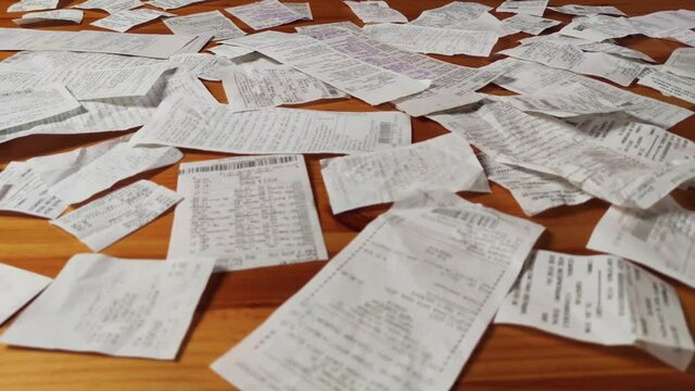 Cash register receipts on a wooden table. Home finance, personal finance, money spending. Unconscious consumption