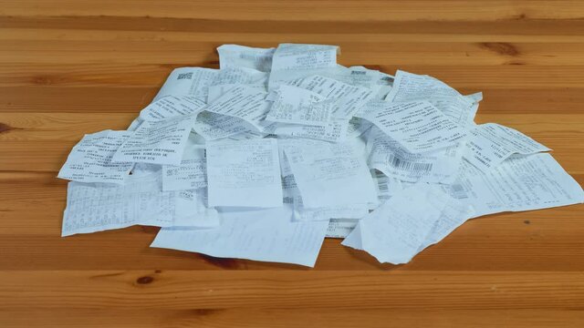 Paper receipt pile. Shopping receipts on a wooden table. Stop motion