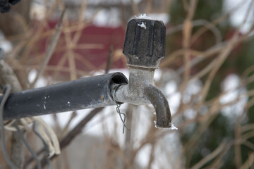 An old water tap, covered with snow.