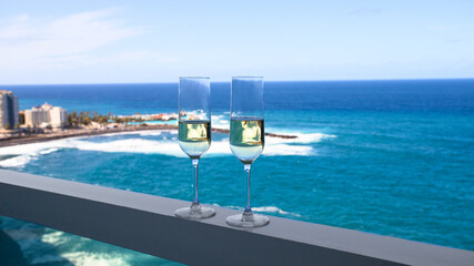 Fototapeta na wymiar Banner for romantic vacation concept. Two champagne glass on hotel balcony with beautiful ocean view in tropical country.