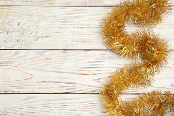 Golden tinsel on white wooden background, top view. Space for text