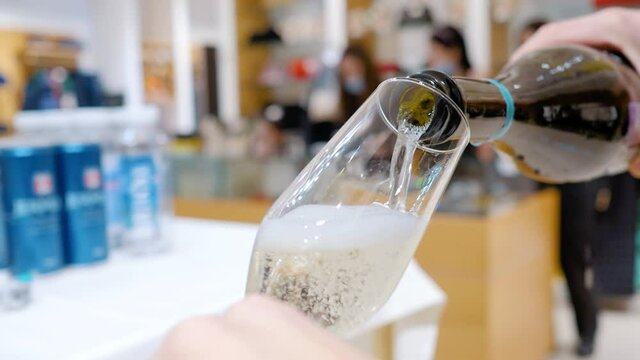 The bartender pours a glass of sparkling wine or champagne. Close-up