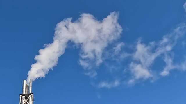 Smoke from a chimney against a clear blue sky.