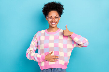 Portrait of attractive cheerful wavy-haired girl touching belly showing thumbup isolated on bright blue color background © deagreez