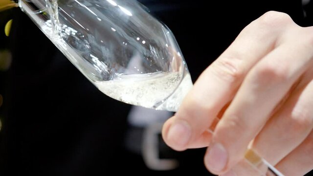 The waiter pours a glass of sparkling wine or champagne. Gold bubbles. Close-up
