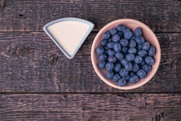 Bowl with blueberries and yogurt on a background of an old wooden surface. Close-up, flat lay