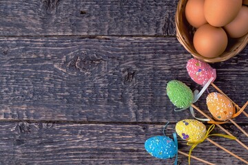 Wicker basket with eggs and decorative bright Easter decorations on the background of the texture of the old wood. Easter holiday concept