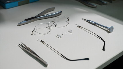 Disassembled glasses frame and tools. Optics work table.