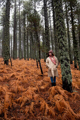 Naklejka premium Young woman in worm clothing standing in the forest in winter.