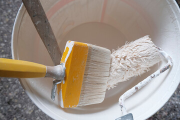bucket of paint and brush on the floor top view. Bucket with white paint. Painting instruments....