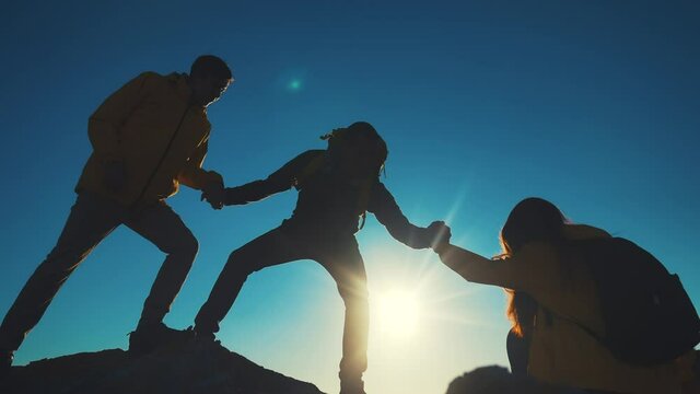 help team concept. team silhouette of climber stretching a helping hand to a friend. business teamwork success concept. silhouette business travel three tourists pull sunlight a helping hand