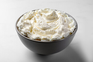 Bowl of tasty cream cheese on white table