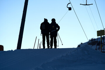 Silhouettes of transport workers at t-bar ski lift in the morning at mountain village Stoos, Canton...