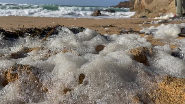 Waves, foam, rock and algae on the sand of the beach