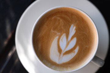 Cup of aromatic coffee with foam on wooden table, top view