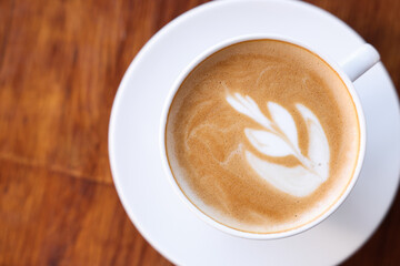 Cup of aromatic coffee with foam on wooden table, top view