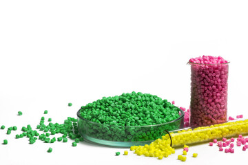 Green, yellow and pink granules of polypropylene or polyamide on a white background. Plastics and...