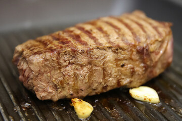 blurred steak beef meat fried in a grill pan, medium roast meat