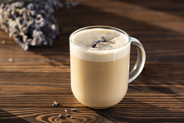 Cappuccino coffee with lavender syrup in a glass mug on a wooden table. Sugar, gluten and lactose free and vegan.