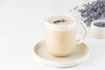 Cappuccino coffee with lavender syrup in a glass mug. Sugar, gluten and lactose free and vegan. Horizontal orientation, copy space.