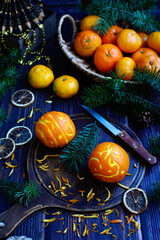 Fototapeta na wymiar Oranges in the form of Christmas balls and tangerines in a basket on a dark wooden background. Gift preparation concept. Vertical