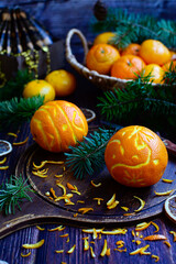 Vertical Christmas composition. Oranges in the shape of Christmas balls and tangerines in a basket on a dark wooden background with fir branches