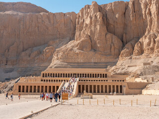 Luxor, Egypt - October 3, 2021: View of the temple of Queen Hatshepsut in the mountains of Egypt. People walk around the territory and inspect the ancient temple.