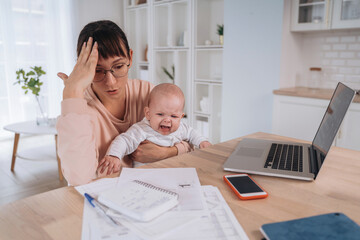 Unhappy frustrated single mother with crying children trying to work at home or solve family...