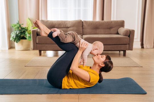 Sport With Baby. Fit Mom Kissing Her Toddler Son While Holding Him On Her Legs And Doing Postpartum Recovery Exercise On Fitness Mat At Home.
Sporty Woman Exercising Together With Her Little Baby