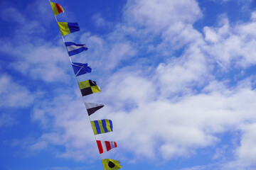 small nautical sea flags on the ship against a blue sky with a cloud. High quality photo