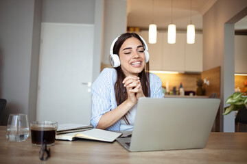 Teenage smiling girl using a laptop and wearing headphones