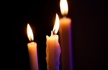 three burning candles on black