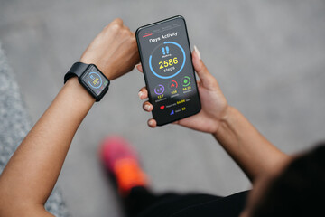 African american lady checking smartphone and smartwatch