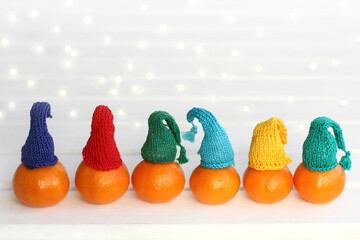 tangerines in different colored hats against the background of festive lights. festive carnival on winter break