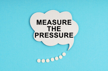 On a blue table are pills and a white plate with the inscription - Measure the pressure