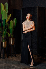 Low key photo of fashion model posing in dress with lace top and deep cut