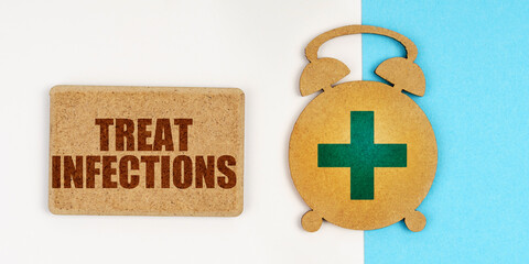 On the white and blue surface are an alarm clock and a sign with the inscription - Treat Infections