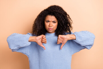 Photo of young woman negative show thumb-down displeased ad rejection isolated over beige color...