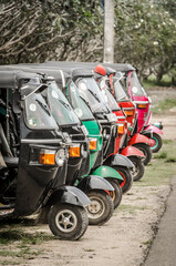 A row of neatly parked tuk tuk auto rickshaws