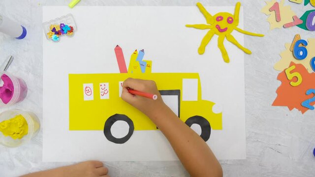 Child making school bus from paper and plasticine. DIY. Back to school, happy time