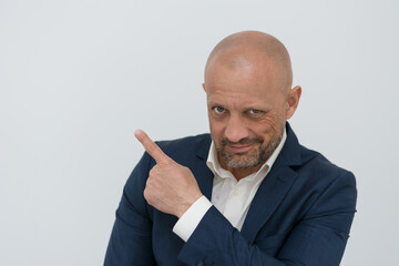 A brutal middle-aged man in a business suit points his finger at the copy pad. A bald man with a shaved head pointed up. Concept: successful businessman.