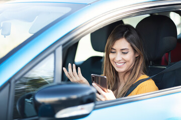 Fototapeta na wymiar Photo of Young beautiful woman drives car looks at screen of mobile phone, uses smartphone, fast paced modern life concept