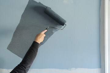 Woman Beginning to Put Fresh Paint on a Wall During a Beroom Restoration.