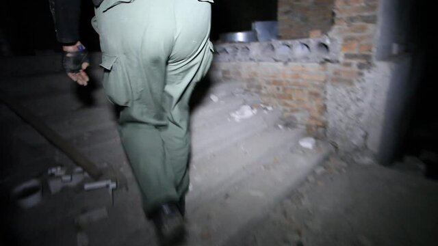 Night search for a missing teenager in an abandoned room. A volunteer climbs an abandoned basement staircase by the light of a flashlight