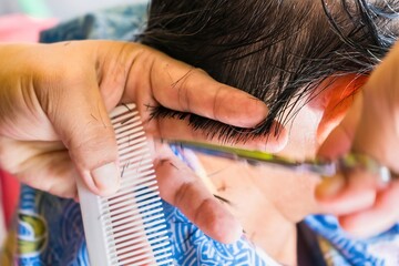Fototapeta premium Bangkok, Thailand - November, 14, 2021 : Close-up of the hairdresser cutting female hair cutting scissors at Bangkok, Thailand.