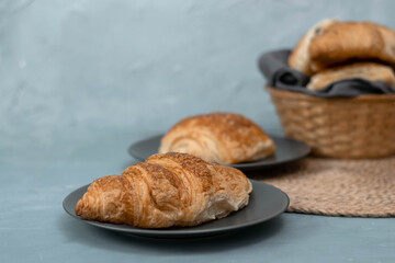 Freshly baked homemade croissants for breakfast. Traditional and whole-grain croissant in a gray plate on a concrete or stone background.