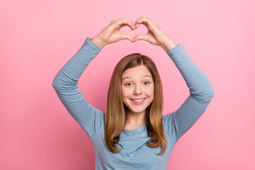 Obraz na płótnie Canvas Portrait of attractive affectionate cheerful brown-haired girl showing heart sign isolated over pink pastel color background