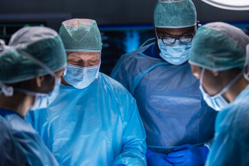 Multiracial team of professional medical surgeons performs the surgical operation in a modern hospital. Doctors are working to save the patient. Medicine, health, cardiology and transplantation.