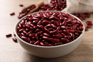 Raw red kidney beans in bowl on wooden table, closeup
