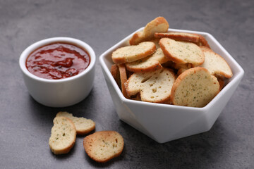 Crispy rusks and dip sauce on grey table, closeup